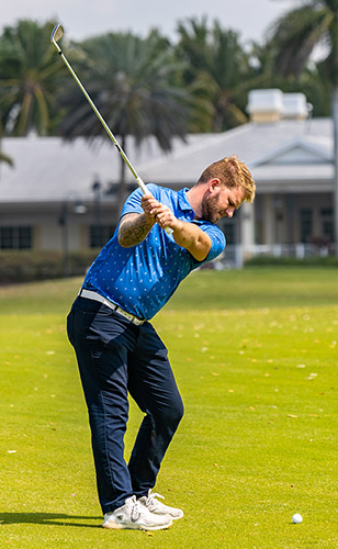 Golf Professional hitting approach shot on the 18th hole of Seven Bridges at Springtree Golf Club